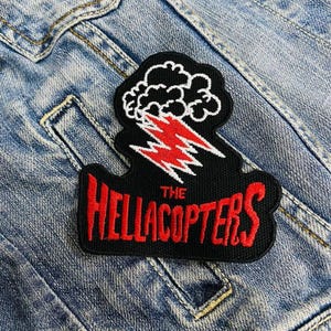 Może przedstawiać: Czarno-czerwona naszywka z haftem przedstawiająca błyskawicę i chmurę. Tekst "THE HELLACOPTERS" jest czerwony.