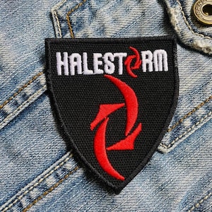 May include: Black and red embroidered patch with the word "HALESTORM" in white lettering. The patch features a red stylized design and is set against a denim jacket.
