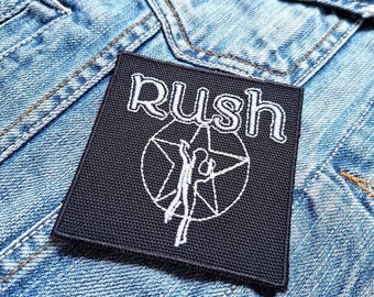Peut inclure: Patch brodé noir avec le mot "Rush" en lettres blanches et une silhouette blanche stylisée dans un cercle.