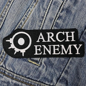 May include: Black and white embroidered patch with the text "ARCH ENEMY" and a stylised sun with a circle in the centre.