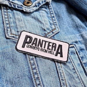 May include: A pink denim jacket with a black patch that reads "Pantera Cowboys From Hell".