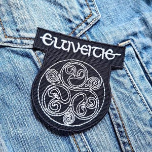 May include: Black and white embroidered patch with the text "Elvenweiche" and a stylized Celtic knot design.