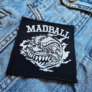 May include: Black and white embroidered patch with the word "MADBALL" in white lettering and a white graphic of a snarling monster with a baseball-like head.