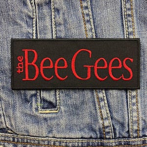 May include: Black embroidered patch with the text "the Bee Gees" in red lettering.