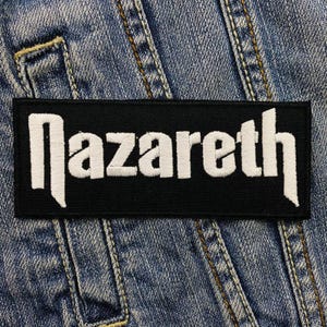 May include: Black patch with white embroidered text "Nazareth" on a denim jacket.