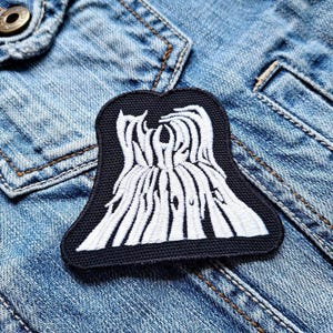 May include: Black and white embroidered patch with the text "WREATH OF BARBS" in a stylized font. The patch is sewn onto a blue denim jacket.