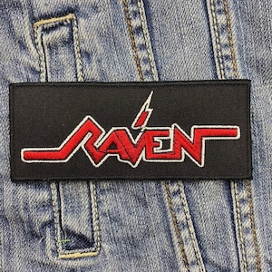 Op de afbeelding: Zwarte patch met rode geborduurde tekst die "RAVEN" luidt met een bliksem boven de tekst.