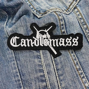 Può includere: Toppa ricamata in bianco e nero con il testo "Candlemass" e un'immagine stilizzata di martelli incrociati.
