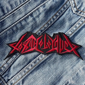 May include: A black and red embroidered patch with the word "SLAUGHTER" in a stylized font.