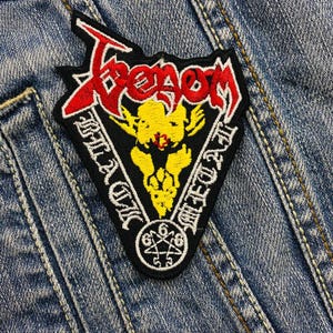 May include: A black and yellow embroidered patch with the word "Venom" in red and white lettering. The patch features a pentagram with the numbers 666 and the words "In the Flesh" and "Die for Metal" in white lettering.