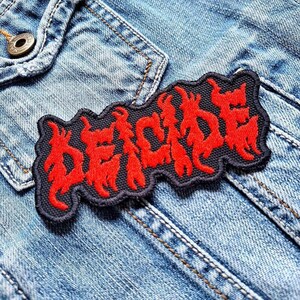 May include: A black and red embroidered patch with the word "DECIDE" in a stylized font. The patch is sewn onto a blue denim jacket.