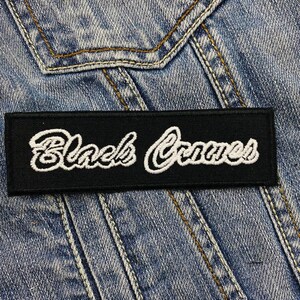 Könnte beinhalten: Schwarzer Canvas-Patch mit weiß gesticktem Text "Black Canvas".