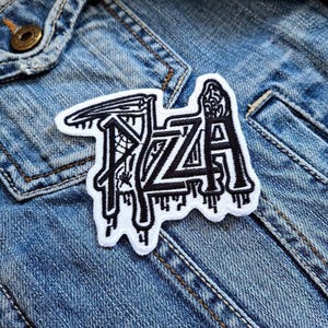 Può includere: Una toppa bianca con cuciture nere che recita "PIZZA" in un font stilizzato. La toppa ha un effetto gocciolante e sembra essere fatta di feltro.