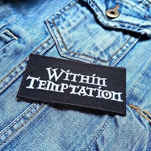 May include: A black patch with white text that reads "Within Temptation" on a blue denim jacket.