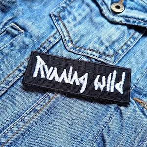 May include: Black fabric patch with white embroidered text that reads "Running Wild".