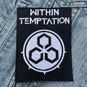 May include: Black rectangular patch with the words "WITHIN TEMPTATION" in white block letters. Below the text is a white and black circular emblem with three interlocking geometric shapes. The patch is on a denim jacket.