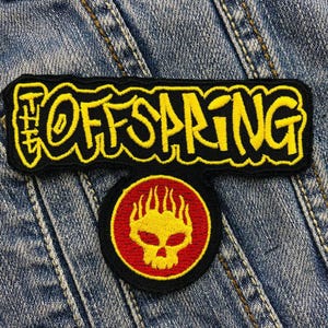 以下が含まれることがあります： 「The Offspring」という文字が書かれた黒と黄色の刺繍パッチと、頭蓋骨と炎が描かれた赤と黄色の刺繍パッチ
