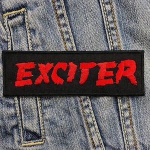 May include: Black and red embroidered patch with the word "EXCITER" in red lettering.