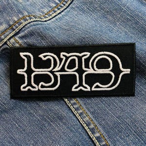 May include: Black patch with white embroidered lettering that reads "B.A.D."