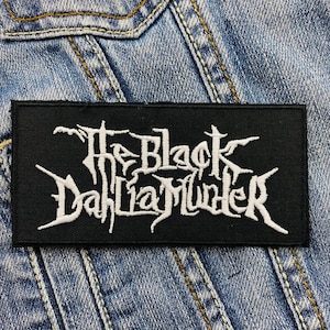Könnte beinhalten: Schwarz-weiß gestickter Patch mit dem Text "The Black Dahlia Murder" auf schwarzem Hintergrund.