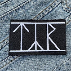 May include: Black patch with white embroidered arrows and a geometric design. The patch has a white border.