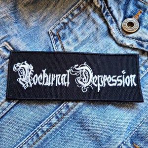 May include: Black embroidered patch with white lettering that reads "Nocturnal Depression".