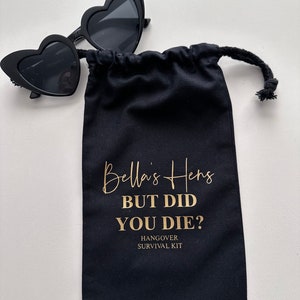 May include: Black fabric bag with a gold drawstring and the text "Bella's Hens But Did You Die? Hangover Survival Kit".