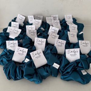 May include: Teal blue satin scrunchies with white tags that say "Emily's Hens Party 25-05-24".