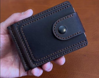 Cartera moderna con clip para billetes y tarjetas y compartimento para monedas.