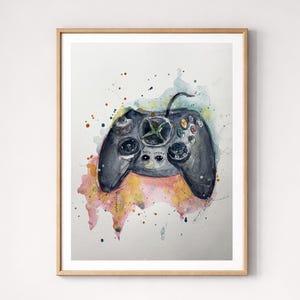 Peut inclure: Peinture à l'aquarelle d'une manette Xbox noire avec des éclaboussures de peinture colorées. La manette est centrée dans un cadre en bois, mettant en valeur les boutons et les joysticks. L'œuvre est exposée sur un mur blanc.