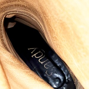 May include: Close-up of the inside of a brown leather boot with a black insole that says "Apus" in white lettering.