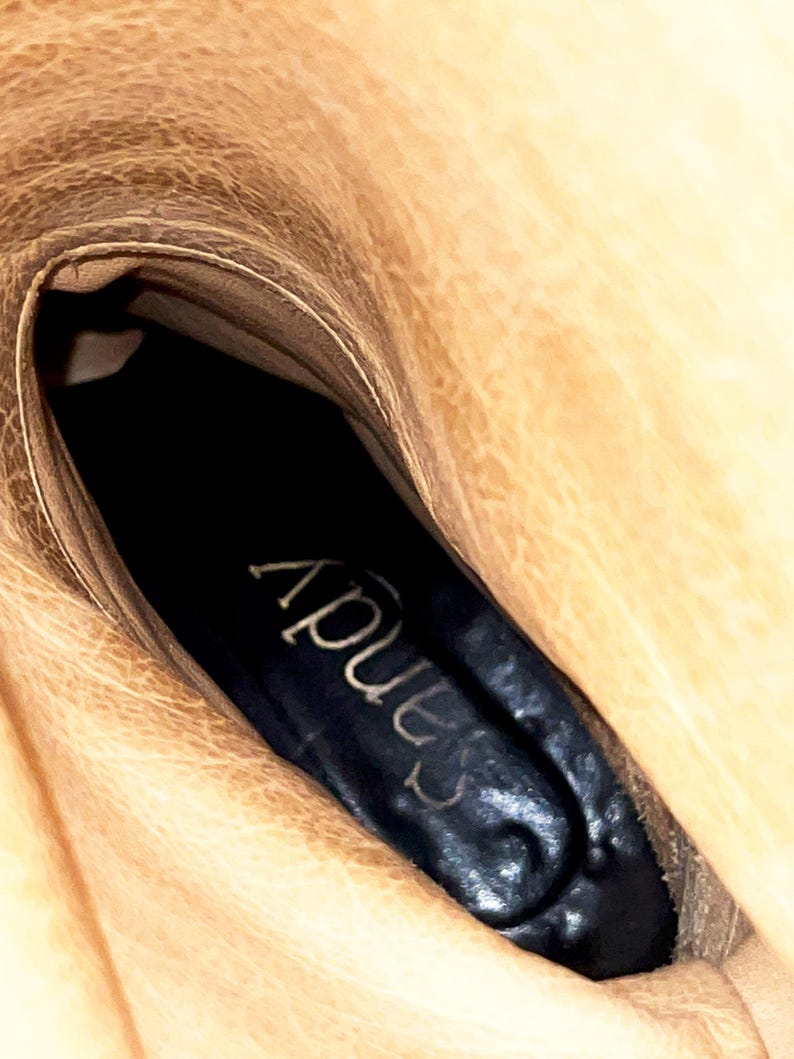 May include: Close-up of the inside of a brown leather boot with a black insole that says "Apus" in white lettering.