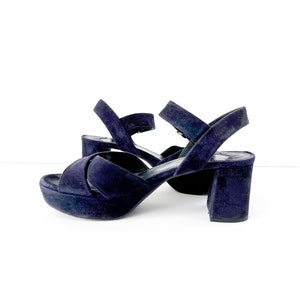 Op de afbeelding: Een paar donkerblauwe su&egrave;de plateau sandalen met een dikke hak. De sandalen hebben een gekruist band ontwerp en een open teen.
