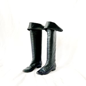 May include: A pair of black leather knee-high boots with a fold-over cuff at the top.