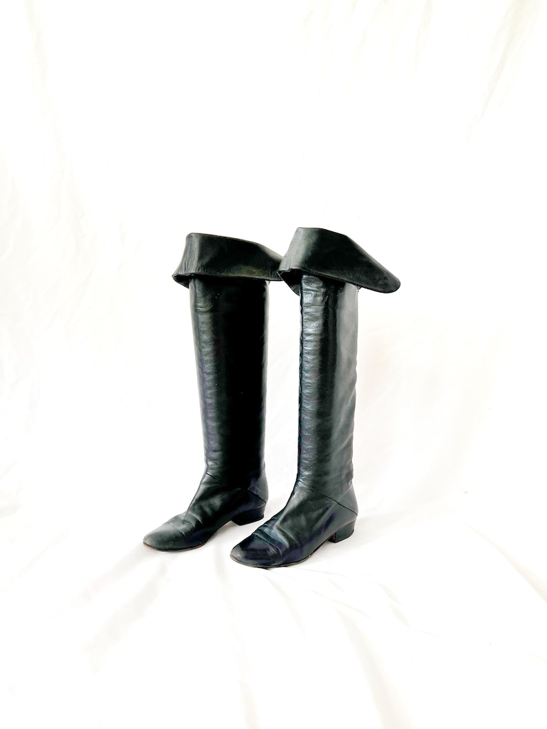 May include: A pair of black leather knee-high boots with a fold-over cuff at the top.