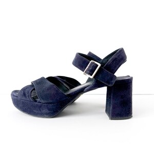 Op de afbeelding: Donkerblauwe su&egrave;de plateau sandalen met een dikke hak en een enkelband met een zilveren gesp.