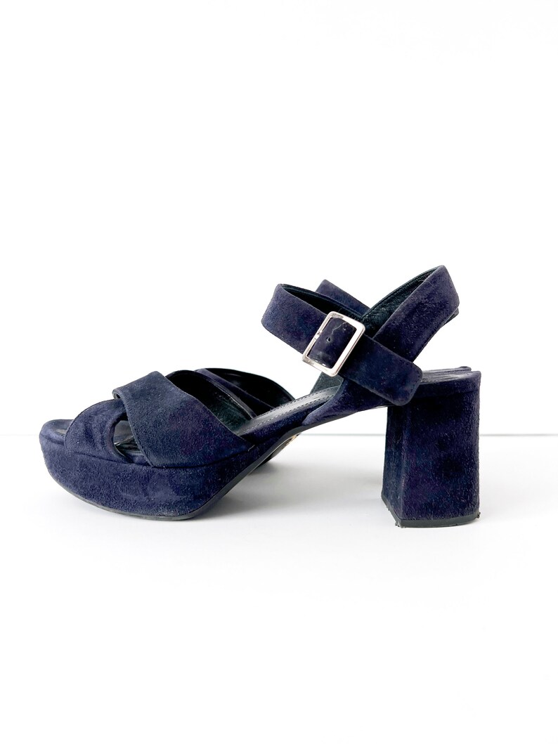 Op de afbeelding: Donkerblauwe su&egrave;de plateau sandalen met een dikke hak en een enkelband met een zilveren gesp.