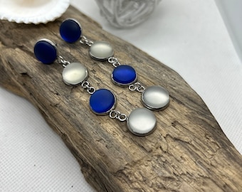 May include: A pair of long silver earrings with alternating blue and white round glass beads.