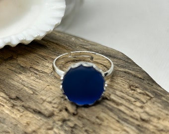 May include: A silver ring with a dark blue oval-shaped stone set in a scalloped bezel.