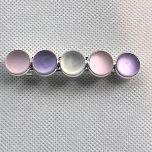 May include: A hair clip with five round, iridescent, pastel-colored stones. The stones are arranged in a row and are set in silver.