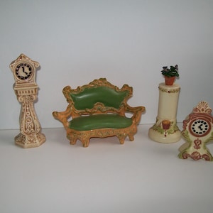 May include: A collection of miniature ceramic furniture, including a grandfather clock, a loveseat, a plant stand, and a small clock. The pieces are painted in shades of beige, green, and orange, with intricate detailing.