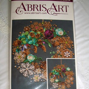 May include: Abris Art craft kit featuring a beaded wreath design. The wreath includes bronze, teal, and purple beaded flowers and snowflake accents. The kit's packaging is white and has the Abris Art logo and website address.