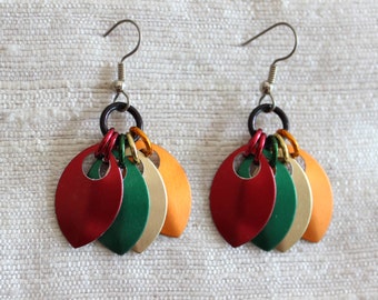 May include: A pair of earrings with five layered metal leaves in red, green, cream, and orange. The leaves are attached to a silver hook.