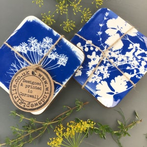 May include: Two blue and white coasters with a floral design. The coasters are tied together with twine and have a brown tag that says "www.wildspirit.co.uk Designed & printed in Cornwall".