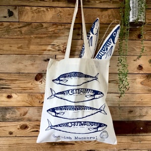 May include: A white canvas tote bag with a blue print of four mackerel fish and the text "Cornish Mackerel".
