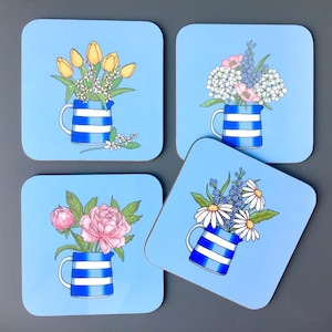 May include: Four blue and white striped ceramic mugs with different floral arrangements. Each mug is on a light blue square coaster.