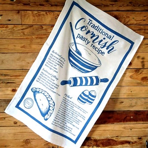 May include: A white tea towel with a blue print of a traditional Cornish pasty recipe. The recipe includes ingredients for the pastry and filling, as well as instructions for making the pasty. The text reads "Traditional Cornish pasty recipe".