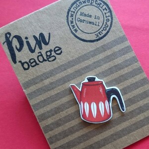 May include: Red and white enamel pin badge of a vintage style coffee pot. The pin badge says "pin badge" and "Made in Cornwall" on the back.