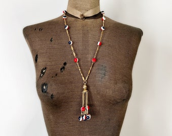 Collana con ciondolo nappa mod vintage. Maglie in metallo color oro e perline rotonde blu, rosse e bianche