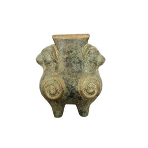 May include: A bronze vase with a square top and two ram heads on the sides. The vase has a green patina and is decorated with spiral designs.